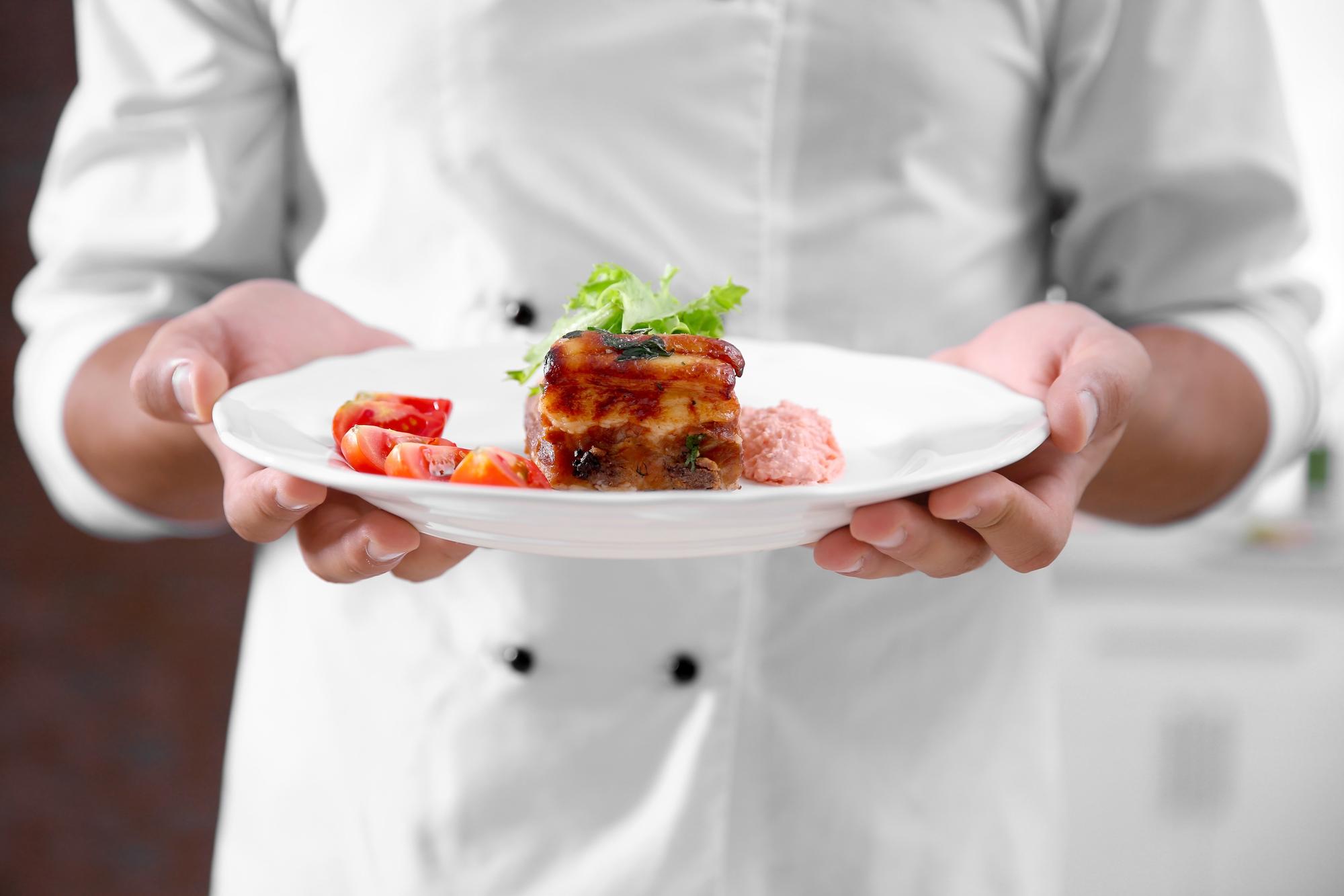 Chef arranging plated dish in a modern kitchen